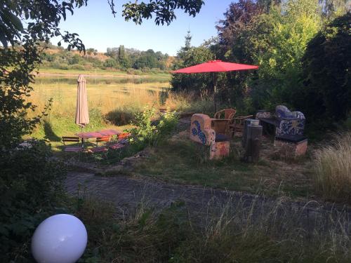 a group of chairs and an umbrella next to a lake at Pension Elbkiosk in Kleinzadel