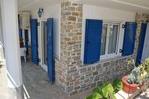 a house with blue shuttered windows and a brick wall at Traditional summer house in Marmari in Marmarion