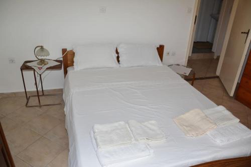 a bed with white sheets and white towels on it at Traditional summer house in Marmari in Marmarion