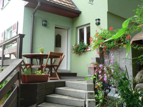 a small house with a porch with a table and flowers at Gite de la Lisière du Bois in Ueberstrass