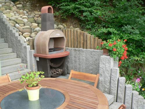 a outdoor table with a pizza oven in a backyard at Gite de la Lisière du Bois in Ueberstrass