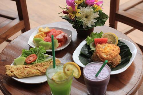 a wooden table topped with plates of food and drinks at Ayuna Family Ubud in Ubud