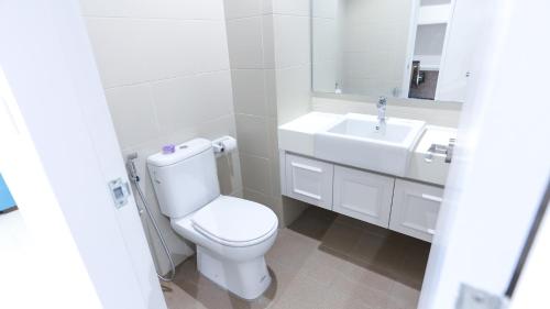 a white bathroom with a toilet and a sink at HostaHome Suites at I-City, Central Mall in Shah Alam