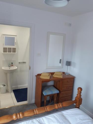 1 dormitorio con escritorio, lavabo y espejo en Lecale Bliss en Downpatrick
