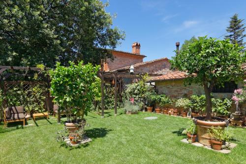 a garden with trees and potted plants and a house at Bed & Breakfast Bel Giorgio in Orentano