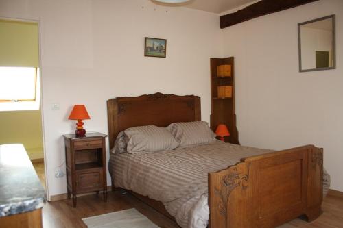 una camera con letto e comodino con lampada di Le Petit Mingot a Druy-Parigny