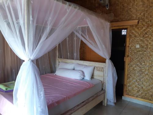 een slaapkamer met een bed met een klamboe bij Friend House SURF & STAY in Airsatang