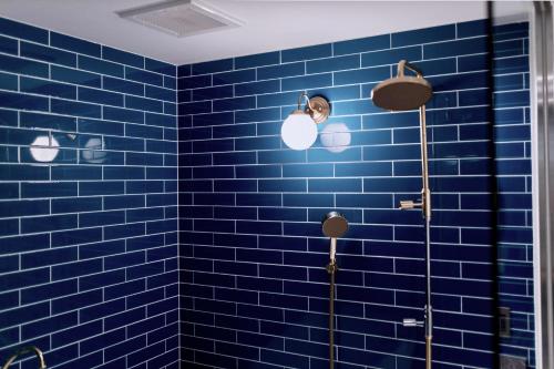 a blue tiled bathroom with a man taking a picture at THE ROOT2 HOTEL in Kyoto