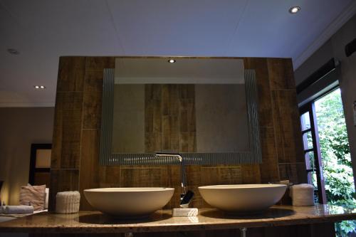 a bathroom with two sinks on a counter with a mirror at Waterfalls Boutique Hotel in Pretoria