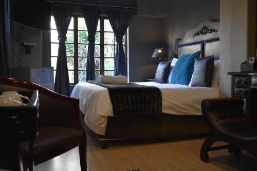 a bedroom with a bed with blue pillows and a chair at Waterfalls Boutique Hotel in Pretoria