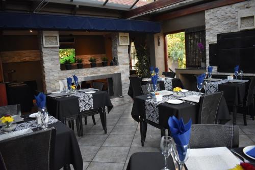 a restaurant with black tables and chairs and a fireplace at Waterfalls Boutique Hotel in Pretoria