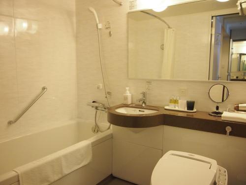 a bathroom with a toilet and a sink and a tub at Hotel TAU, Kumamoto in Kumamoto