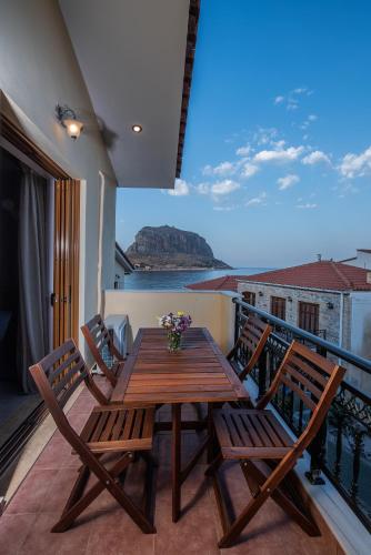 a wooden table and chairs on a balcony with a view at Cyrenia Guesthouse in Monemvasia