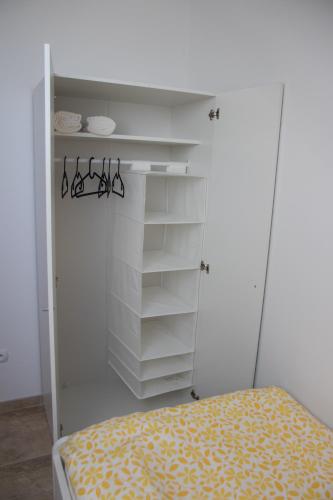 a bedroom with a closet with white shelves and a bed at Apartmán U Fuxů in Žleby