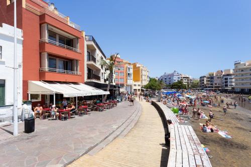 a beach with people sitting on the sand and a boardwalk at Amazing Beachfront Property CASA CORINA I in El Médano