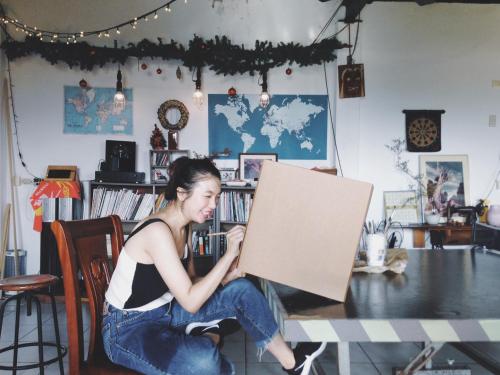 a young woman sitting on a table holding a canvas at Puli Islet Inn in Puli