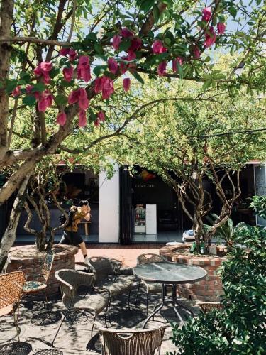 a table and chairs under a tree with pink flowers at Puli Islet Inn in Puli