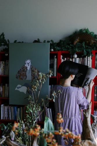 a woman holding a book in front of a book shelf at Puli Islet Inn in Puli