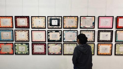 a person looking at a display of art on a wall at Puli Islet Inn in Puli