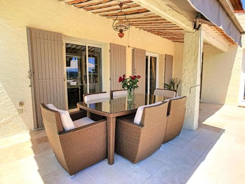 a patio table with chairs and a vase of flowers at 3 Bedrooms Villa near Cannes - Pool & Jacuzzi - Sea View in Mandelieu-La Napoule