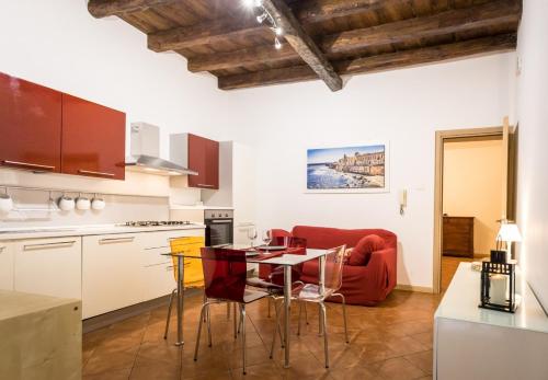 eine Küche mit einem Tisch und einem roten Sofa in der Unterkunft La Casa di Manu Ortigia in Syrakus