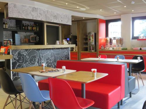 un restaurant avec des tables et des chaises rouges et bleues dans l'établissement ibis Soissons, à Soissons