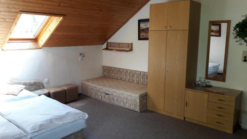 a bedroom with a bed and a bench and a window at pension Jesen in Benecko