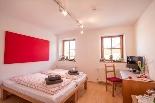 twee bedden in een kamer met een rode muur bij Hormannhof in Linden