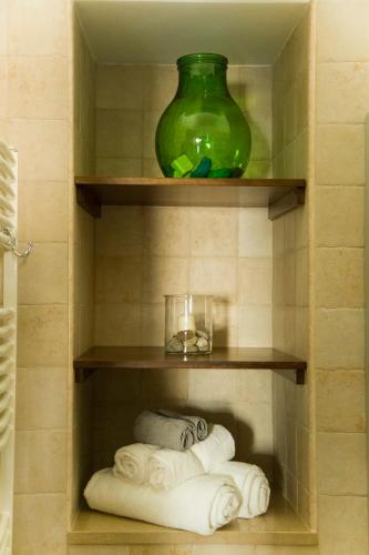 a bathroom with a green vase and towels on shelves at Acqua Cotta in Trani