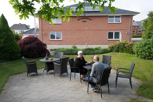 two people sitting at a table in a yard at Agerskov Kro & Hotel in Agerskov