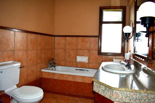 La salle de bains est pourvue de toilettes, d'un lavabo et d'une baignoire. dans l'établissement Lake Nakuru Lodge, à Nakuru