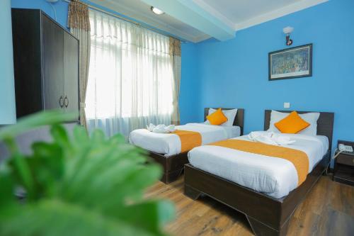 two beds in a room with blue walls at Hotel Access Nepal in Kathmandu