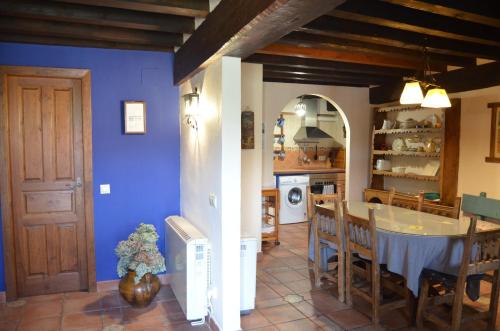 cocina y comedor con paredes azules y mesa en Casa Rural La Casa de Piedra, en Navarredonda de Gredos
