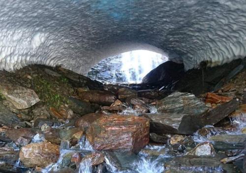 an ice tunnel with rocks and water in it at Hotell Klimpfjäll in Klimpfjäll