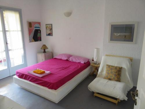 a bedroom with a pink bed and a chair at Οντας της Αθηνάς in Gialiskari