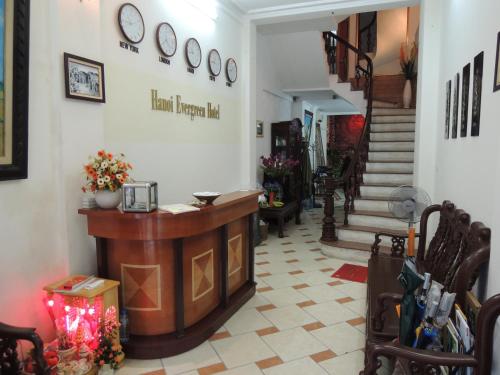 a room with a counter and a staircase with clocks on the wall at Hanoi Ecogreen Hostel in Hanoi