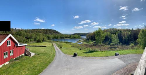 a dirt road next to a red building and a river at Sju Sjöar in Hyltenäs