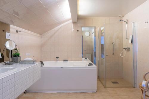 ein weißes Bad mit einer Badewanne und einer Dusche in der Unterkunft First Hotel Statt Örnsköldsvik in Örnsköldsvik