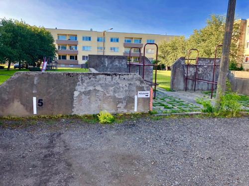 an abandoned playground in a park with a building in the background at Wind Rose apartment in Kuressaare