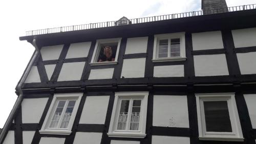 a man looking out of a window of a black and white building at Pilgrims Gästeapartements in Meschede