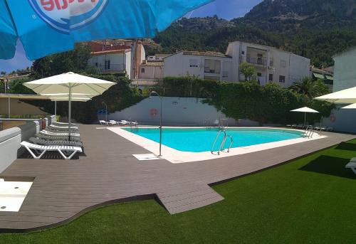 a swimming pool with chairs and umbrellas next to a building at Albergue Inturjoven Cazorla in Cazorla