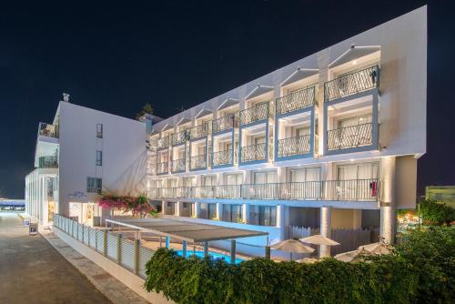 a large white hotel with a swimming pool at night at Alia Beach Hotel by Estia in Hersonissos