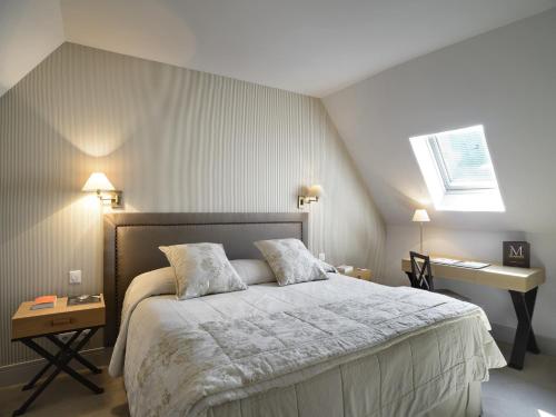 a bedroom with a large bed and a desk at Les Manoirs de Tourgéville in Deauville