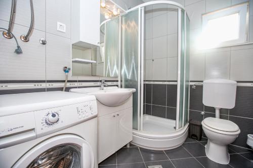 a bathroom with a washer and a toilet and a sink at Apartments Villa Dina in Karlobag