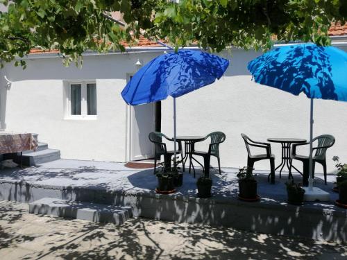 een tafel en stoelen met blauwe parasols bij Sara apartments in Budva