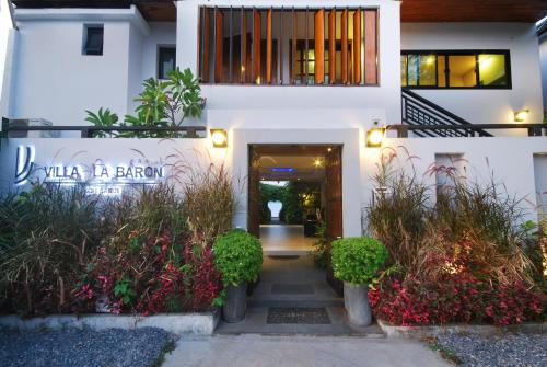 a front entrance to a white building with plants at Villa Labaron in Koh Samui 