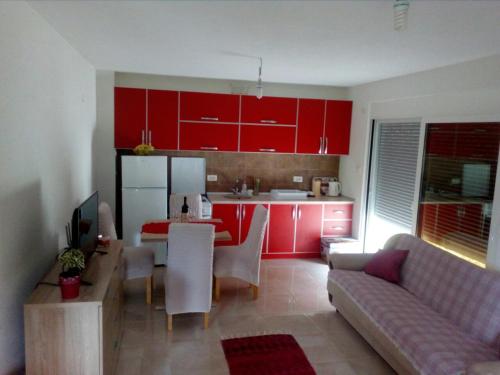 a kitchen with red cabinets and a living room at Apartman Strahinja in Tivat