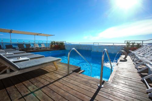 a swimming pool with chairs on a wooden deck at Capsis Astoria Heraklion in Heraklio Town