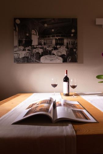 an open book on a table with two glasses of wine at HOTEL AD Residence in Bormio