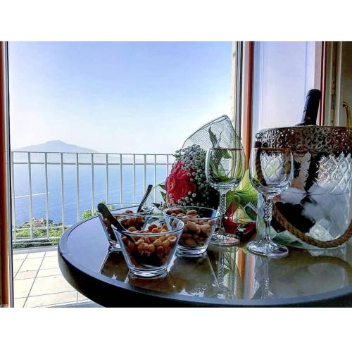 a table with wine glasses and a view of the ocean at Villa Mariagiovanna - Casa Giovanna in Vico Equense